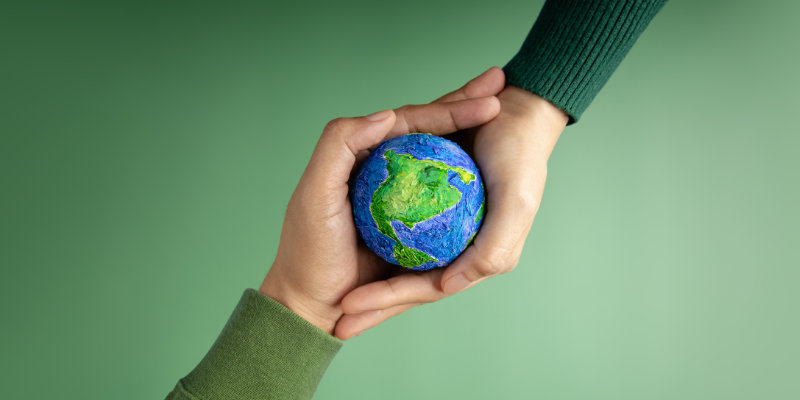 Two hands holding a small Earth ball