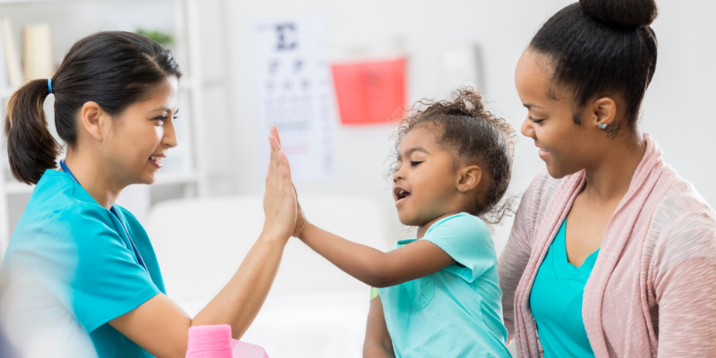 Child with her mother and a healthcare provider in a clinical setting 